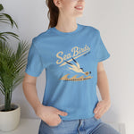 Jacksonville Beach Sea Birds Premium Lightweight T-Shirt in ocean blue with the diving shorebird skimming over waves in navy script lettering on the front, worn by model