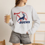 Bend Bucks Crewneck Sweatshirt in ash with the Bend Bucks logo, a leaping buck over a red-stitched baseball on the front, worn by model
