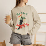 Miami Hustlers Crewneck Sweatshirt in sand with the mustached man in a striped vest holding playing cards and a bat on the front, worn by model