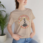 St. Augustine Saints Premium Lightweight T-Shirt in tan with the black and white striped lighthouse emblem with gold rays on the front, worn by model