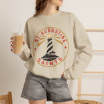 St. Augustine Saints Crewneck Sweatshirt in sand with the black and white striped lighthouse emblem with gold rays on the front, worn by model