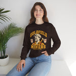 Goldfield Miners Crewneck Sweatshirt in dark chocolate with the Goldfield Miners logo, a mustached miner with a candle on his cap and a pickaxe on his shoulder on the front, worn by model