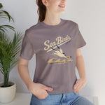 Jacksonville Beach Sea Birds Premium Lightweight T-Shirt in pebble brown with the diving shorebird skimming over waves in navy script lettering on the front, worn by model