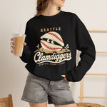 Seattle Clamdiggers Crewneck Sweatshirt in black with the Seattle Clamdiggers logo, a clam shell made from a baseball half-buried in a tide flat on the front, worn by model