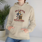 Olympia Senators Hoodie in sand with the Olympia Senators logo, a bearded senator in a frock coat at a podium with a bat on the front, worn by model
