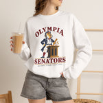 Olympia Senators Crewneck Sweatshirt in white with the Olympia Senators logo, a bearded senator in a frock coat at a podium with a bat on the front, worn by model