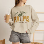Fort Myers Palms Crewneck Sweatshirt in sand with the palm tree between bold gold block letters with a baseball on the front, worn by model
