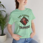 Las Cruces Farmers Premium Lightweight T-Shirt in mint with the Las Cruces Farmers logo, a red chile pepper pitcher in a high-kick windup on a brown diamond, with Farmers in brown block letters on the front, worn by model