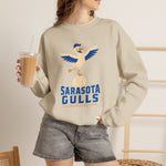 Sarasota Gulls Crewneck Sweatshirt in sand with the cream cartoon gull balancing on a baseball with wings spread on the front, worn by model