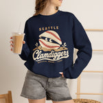 Seattle Clamdiggers Crewneck Sweatshirt in navy with the Seattle Clamdiggers logo, a clam shell made from a baseball half-buried in a tide flat on the front, worn by model