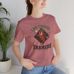 Las Cruces Farmers Premium Lightweight T-Shirt in heather mauve with the Las Cruces Farmers logo, a red chile pepper pitcher in a high-kick windup on a brown diamond, with Farmers in brown block letters on the front, worn by model