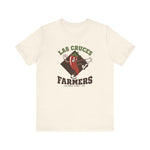 Las Cruces Farmers Premium Lightweight T-Shirt in natural with the Las Cruces Farmers logo, a red chile pepper pitcher in a high-kick windup on a brown diamond, with Farmers in brown block letters on the front