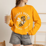 Bisbee Bees Crewneck Sweatshirt in gold with the Bisbee Bees logo, a cartoon bee in a ball cap catching a baseball on the front, worn by model