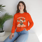 Tucson Cowboys Crewneck Sweatshirt in orange with the Tucson Cowboys logo, a cowboy in front of a saguaro with 1941 and 1953 pennant banners on the front, worn by model